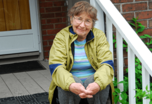 Senior sitting on the stairs wearing an olive jacket