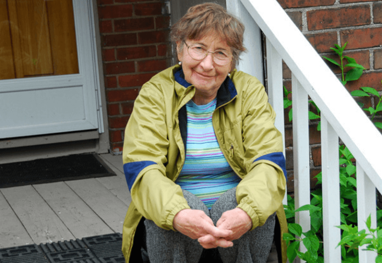 Senior sitting on the stairs wearing an olive jacket