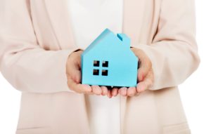 Elderly business woman holding blue paper house