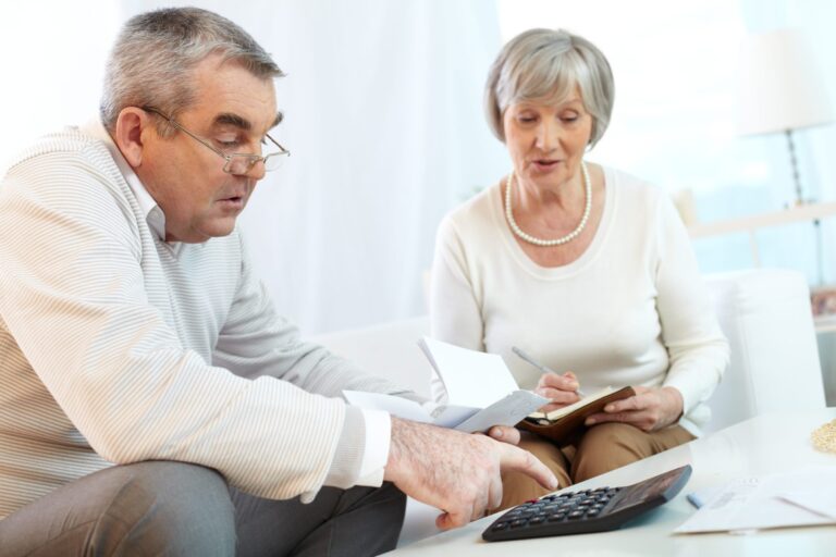 Two old people talking, writing, and using a calculator