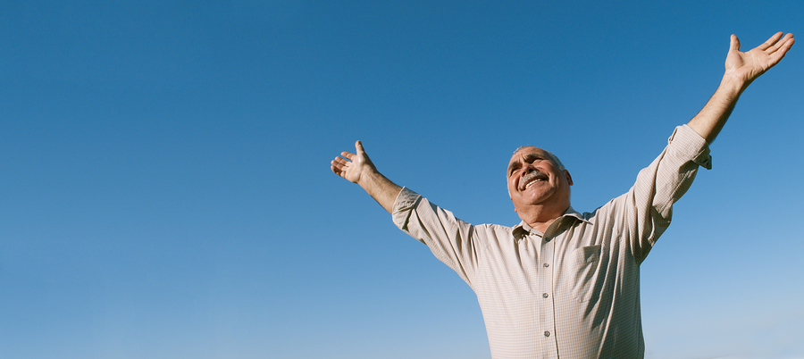 An old man raising his hands towards the sky