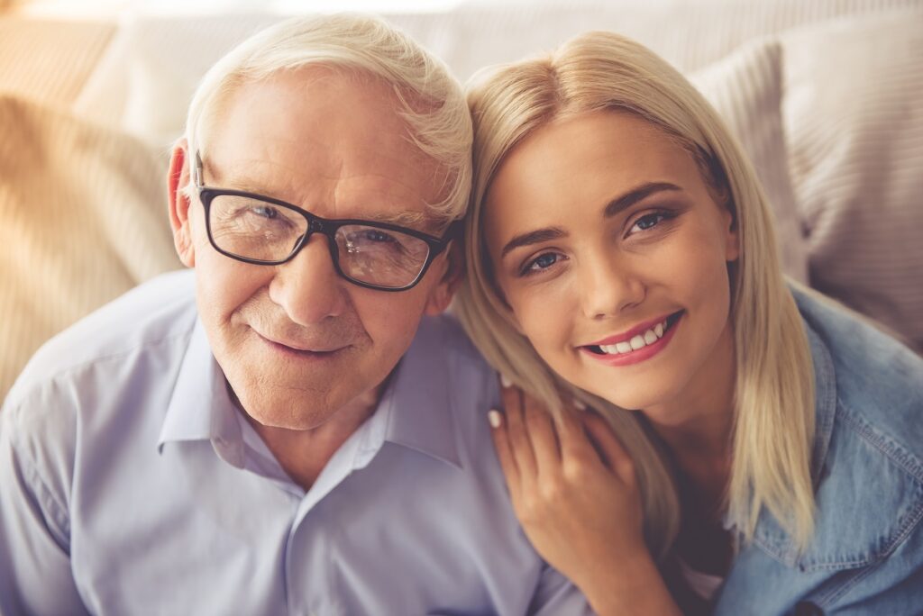 An older man and a young woman posing for a photo.