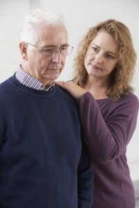 A woman is standing next to an older man.