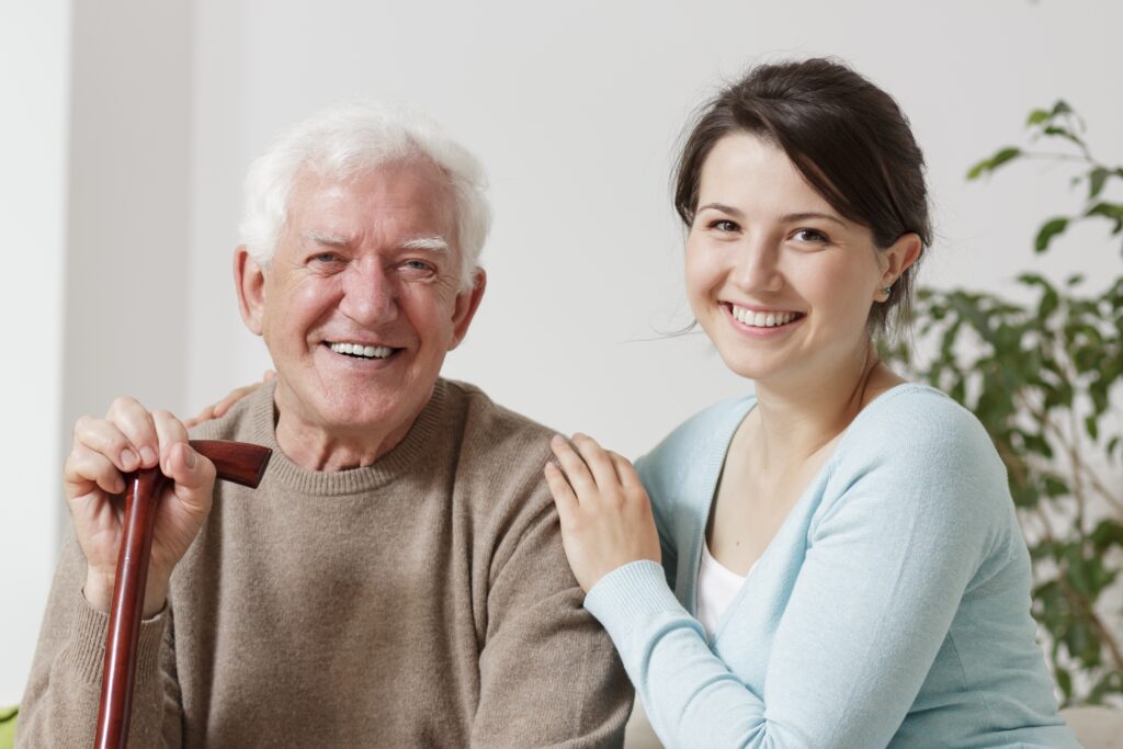 A woman and an elderly man are smiling together.