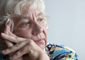 An old woman with white hairs thinking with hands on chicks