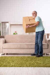 A man carrying a box in his living room.